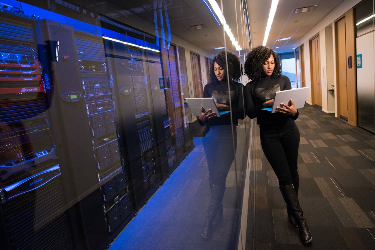 services-08 A woman using a laptop navigating a contemporary data center with mirrored servers.