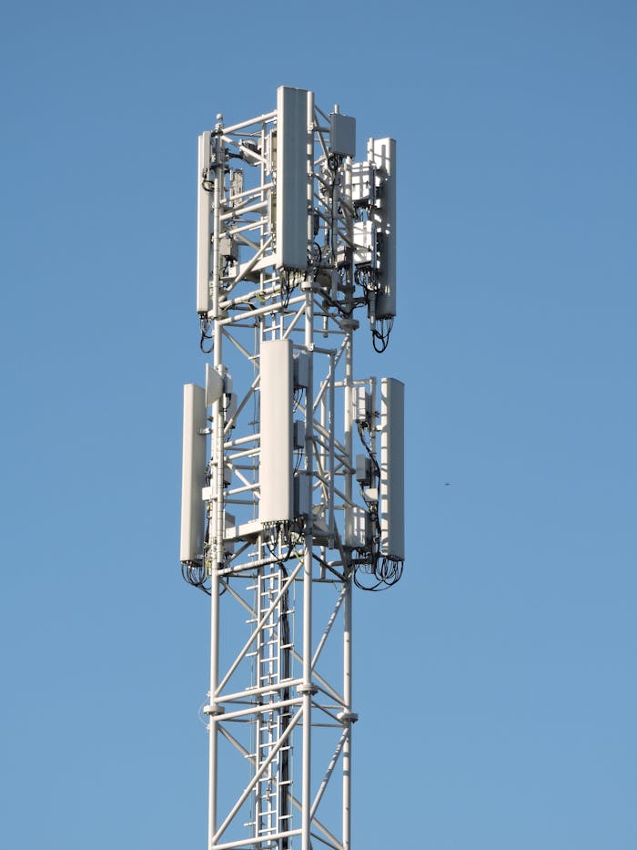 gallery-04 Close-up of a communication tower with antennas against a clear blue sky, emphasizing modern technology.