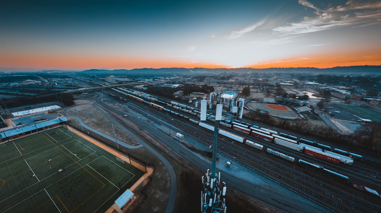 portfolio-02 Aerial view of industrial district of Chattanooga city with green rugby fields and modern cell tower located near railroad tracks against sunset sky