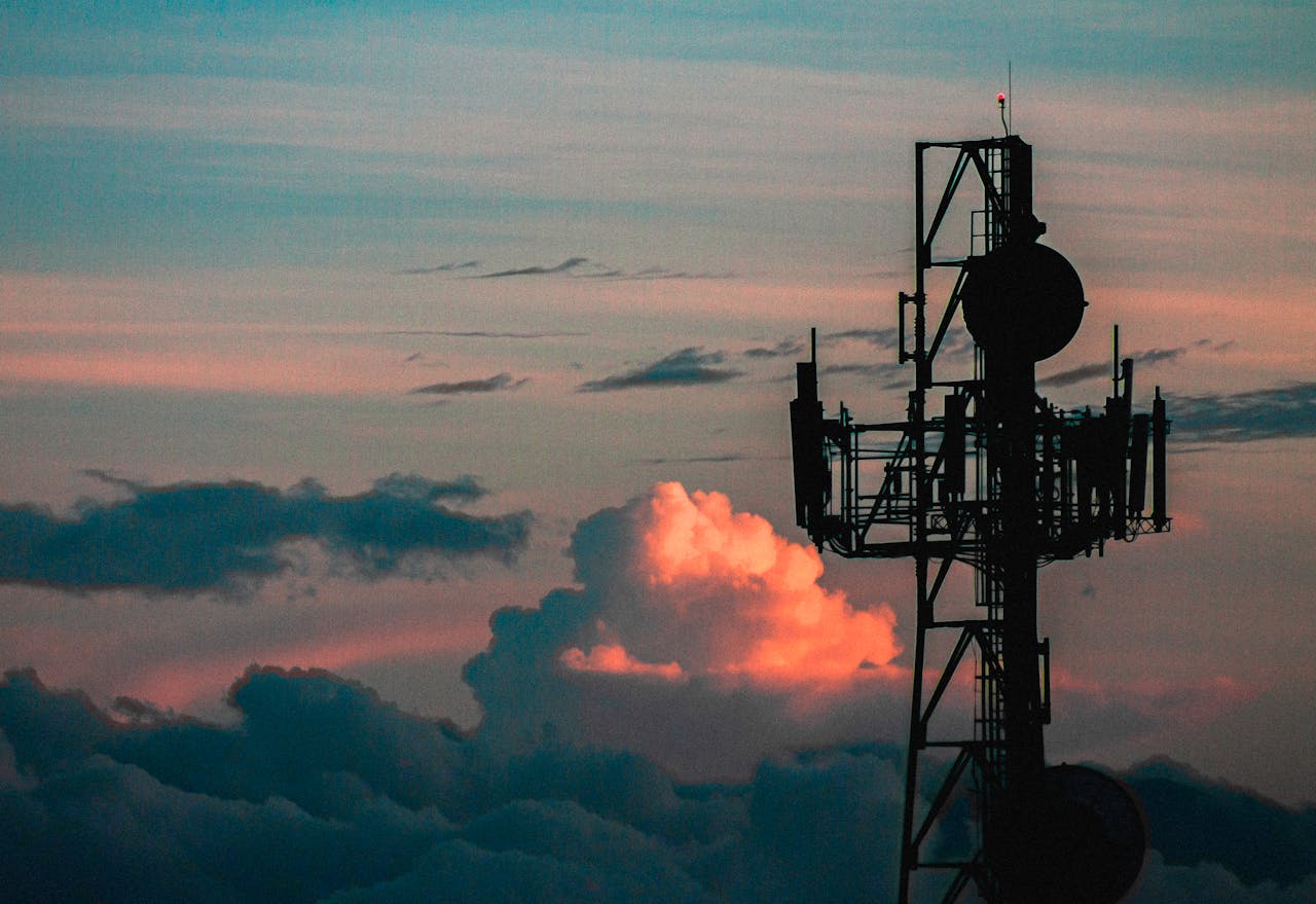 gallery-01 A communication tower silhouette against a colorful sky with vibrant sunset clouds.